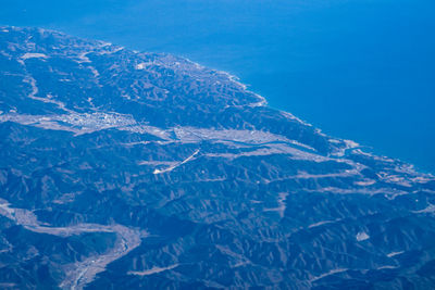 Aerial view of snowcapped mountains against blue sky