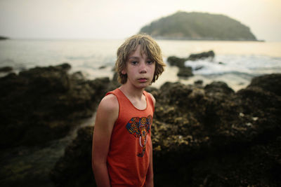 Portrait of boy standing against sea during sunset