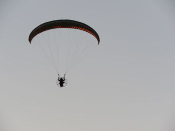 Low angle view of person paragliding against clear sky