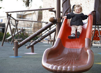 Baby girl sliding,warm clothing child,kid,toddler, infant of 1-2 year having fun in playground 