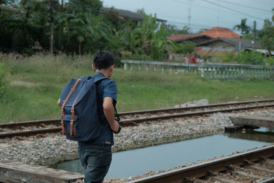 Rear view of man standing by railroad tracks