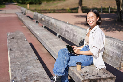 Portrait of young woman sitting on wood