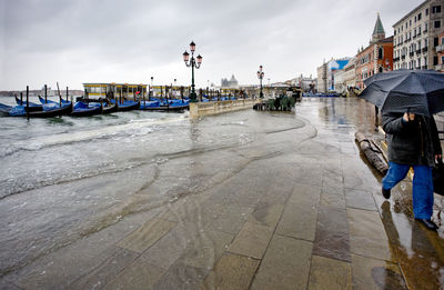 Gondolas moored at grand canal by santa maria della salute against sky