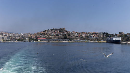 Sea by buildings in city against sky