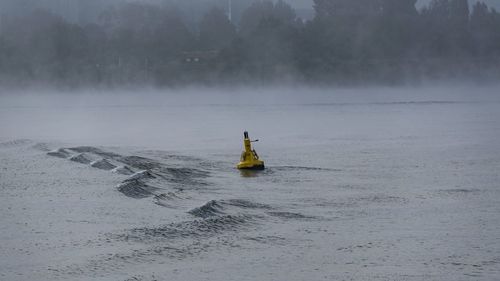 Distance marker in river during rain