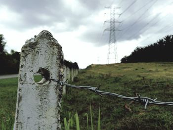 Close-up of barbed wire on grass against sky