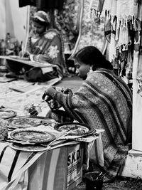 Rear view of a hard working woman sitting in market and making handicrafts