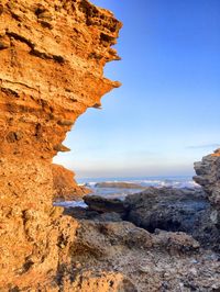 Rock formations by sea against clear sky