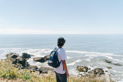 Rear view of man looking at sea against sky