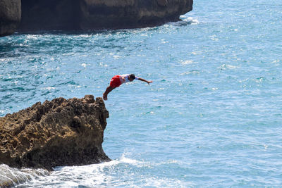 Man surfing on rock in sea