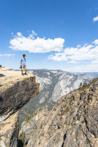 Man standing on rock against sky