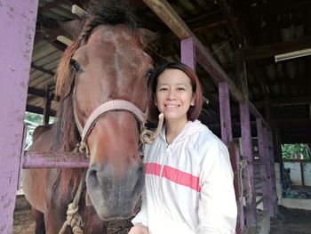 Portrait of smiling young woman standing in stable