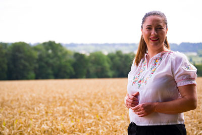 Portrait of smiling young woman standing on field