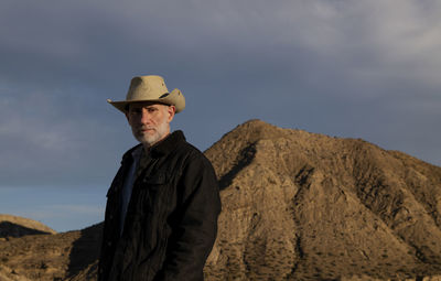 Adult man in cowboy hat standing against mountains in tabernas desert. almeria, spain