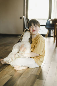 Boy sitting with dog on floor at home