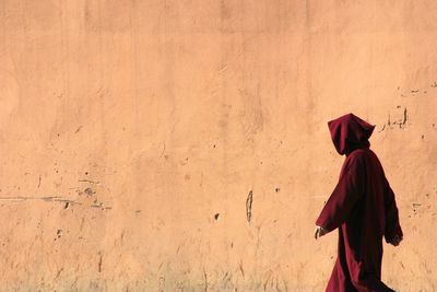 Side view of woman walking by wall