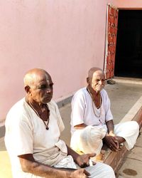 Rear view of people sitting on wall