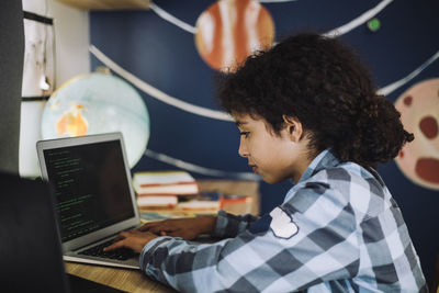 Girl concentrating while learning coding on laptop at home