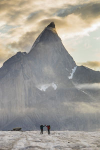 Two backpackers high-five under dramatic mountain