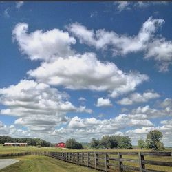 View of field against cloudy sky