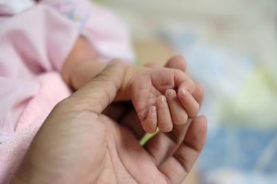 Cropped image of mother holding baby hand