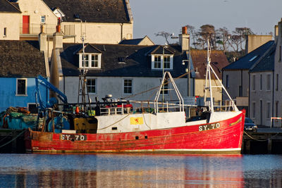 Boats moored at harbor against buildings in city