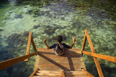 Rear view of woman sitting on wooden railing