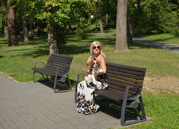 Woman and her dog - cavalier king charles resting on bench in park of vrnjacka banja town in serbia