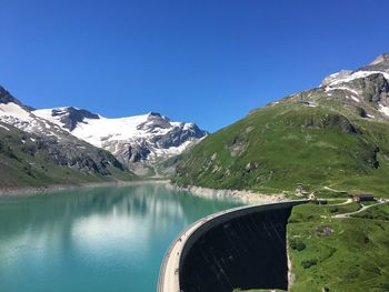 Scenic view of lake and mountains against clear blue sky