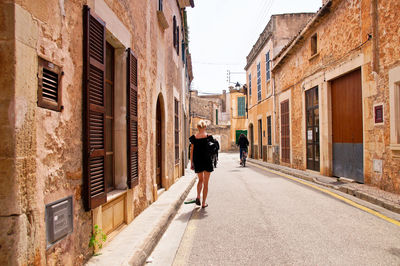 Rear view of man walking on footpath amidst buildings