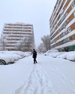 Man walking on snow covered buildings in city
