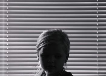 Close-up of girl looking away against window blinds