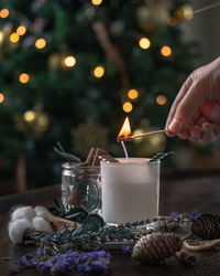 Cropped hand of woman burning candle at home