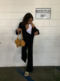 Low section of woman standing against wall, parking garage