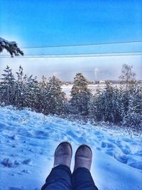 Low section of person standing on snow covered field