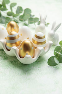 Easter decor. golden easter eggs on a ceramic holder and decorative rabbits. 