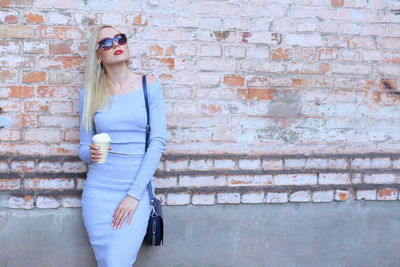 Beautiful woman standing by wall