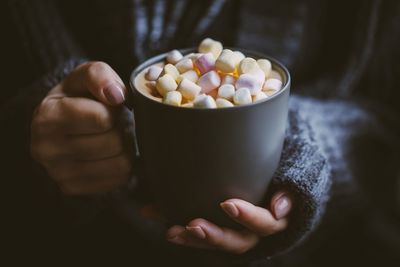 Cropped hands of woman holding marshmallows in coffee cup