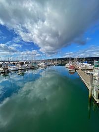 Sailboats moored at harbor against sky