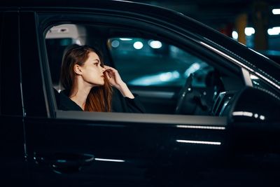 Side view of young woman in car