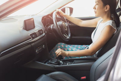 Woman hand on the gear shifter while driving the car.