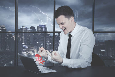 Angry businessman using laptop in office