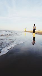 People standing on beach against sky