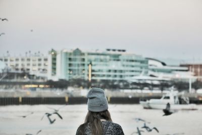 Rear view of woman wearing knit hat against buildings in city