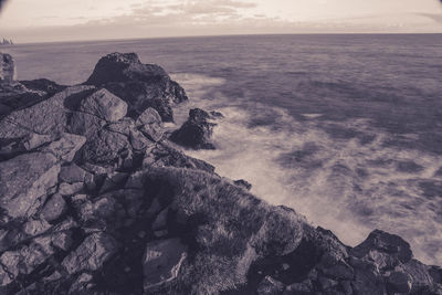 Rock formation on sea shore against sky