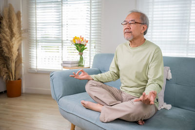 Portrait of young man sitting on sofa at home