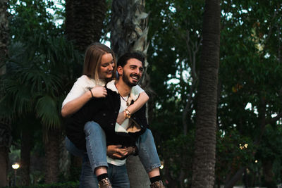 Happy young couple kissing against trees and plants