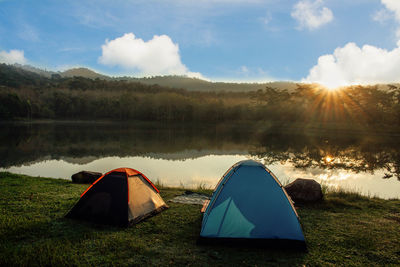 Tent on mountain by lake against sky