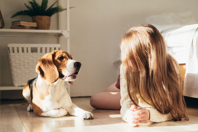 Woman with dog sitting on floor at home