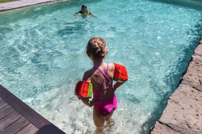 Rear view of girl looking at friend swimming in pool